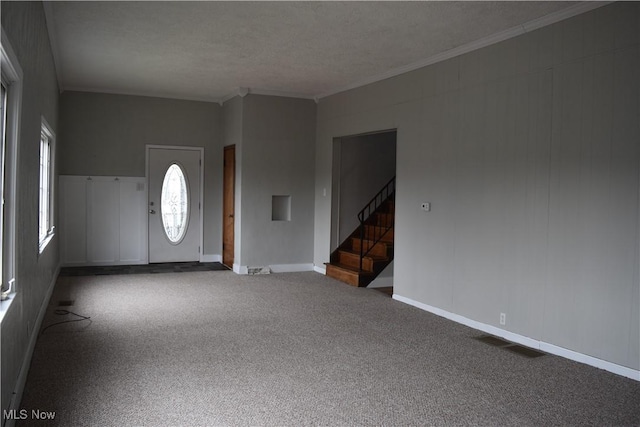 foyer entrance with ornamental molding, carpet flooring, and a textured ceiling