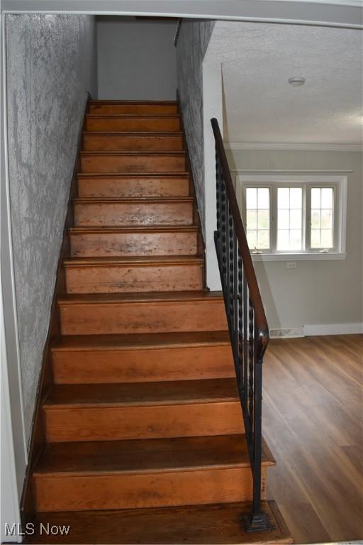 stairway with crown molding and hardwood / wood-style floors