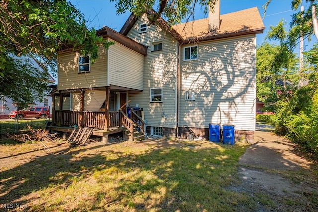 rear view of house with a wooden deck and a lawn