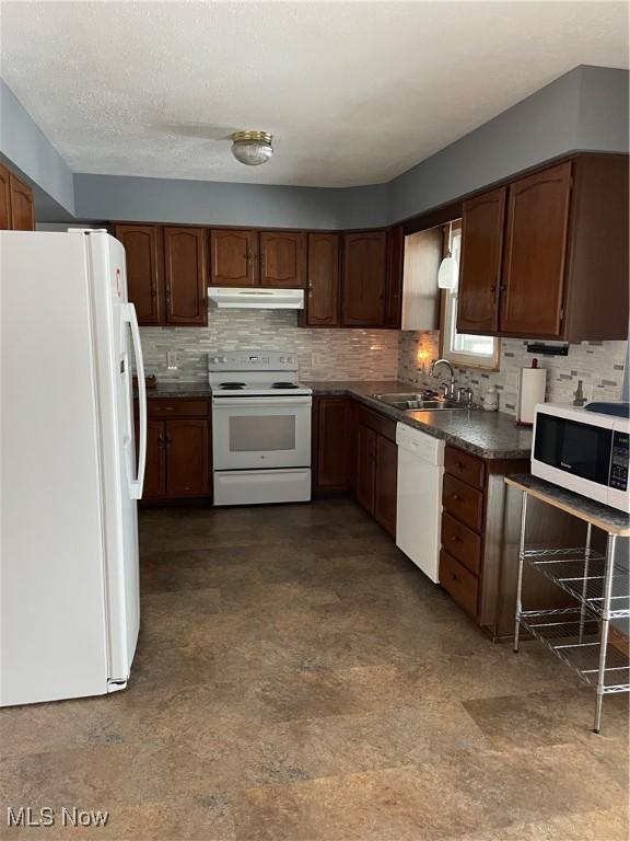 kitchen featuring sink, white appliances, a textured ceiling, and backsplash