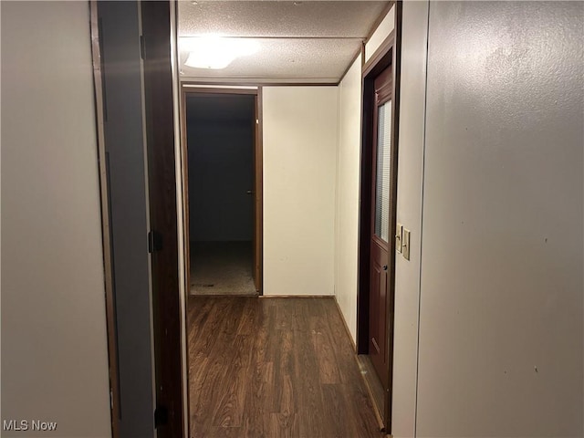 hallway with dark wood-type flooring and a textured ceiling