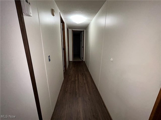 corridor with dark hardwood / wood-style floors and a textured ceiling