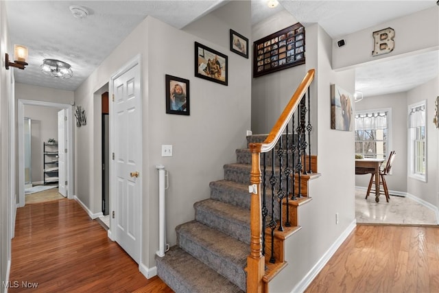 stairway with hardwood / wood-style flooring and a textured ceiling