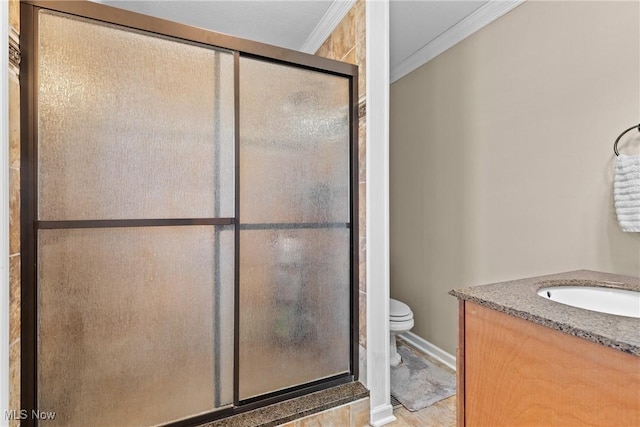 bathroom with vanity, crown molding, a shower with door, and toilet