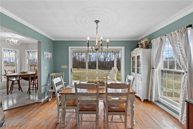 dining space with an inviting chandelier, ornamental molding, and light hardwood / wood-style floors