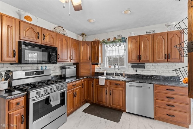 kitchen featuring sink, dark stone countertops, ceiling fan, stainless steel appliances, and backsplash