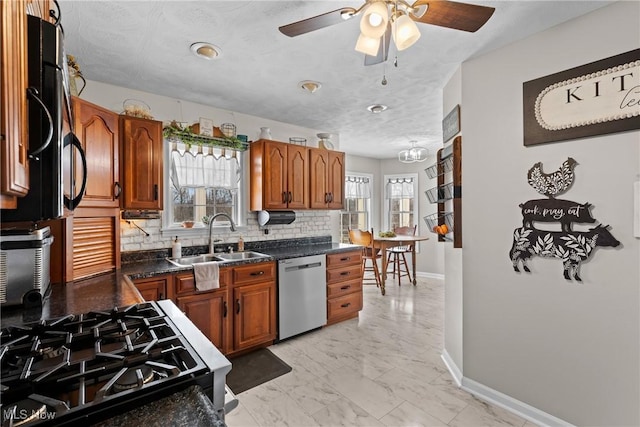 kitchen with gas range, sink, dishwasher, dark stone countertops, and decorative backsplash