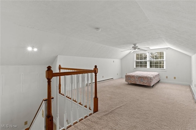 unfurnished bedroom with vaulted ceiling, a baseboard heating unit, light colored carpet, ceiling fan, and a textured ceiling