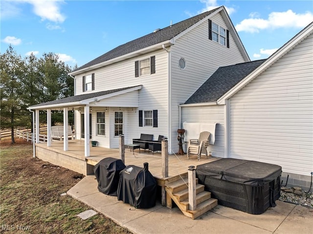 back of property with a hot tub and a deck