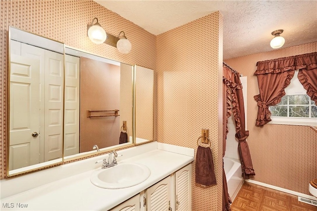 bathroom with vanity, parquet flooring, a textured ceiling, and shower / tub combo with curtain