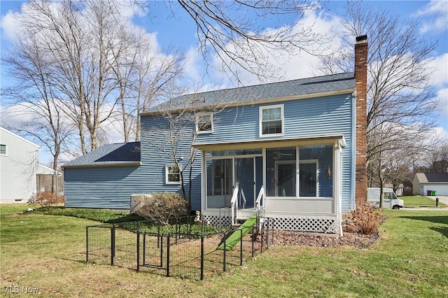 rear view of house with a yard and a sunroom