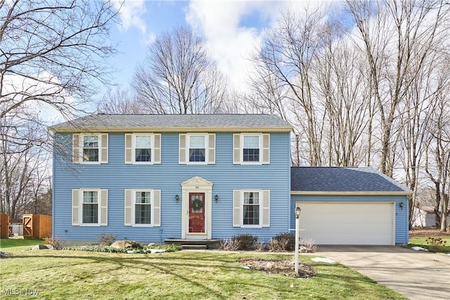 colonial inspired home featuring a garage and a front lawn