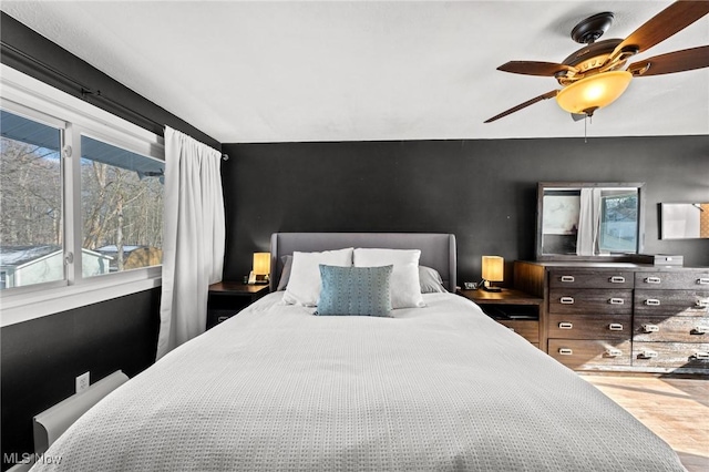 bedroom featuring multiple windows, wood-type flooring, and ceiling fan