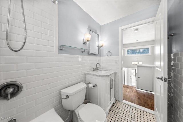 bathroom featuring a shower, tile walls, tile patterned flooring, vanity, and toilet