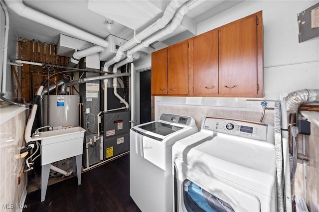 washroom featuring gas water heater, heating unit, dark hardwood / wood-style flooring, cabinets, and washing machine and dryer