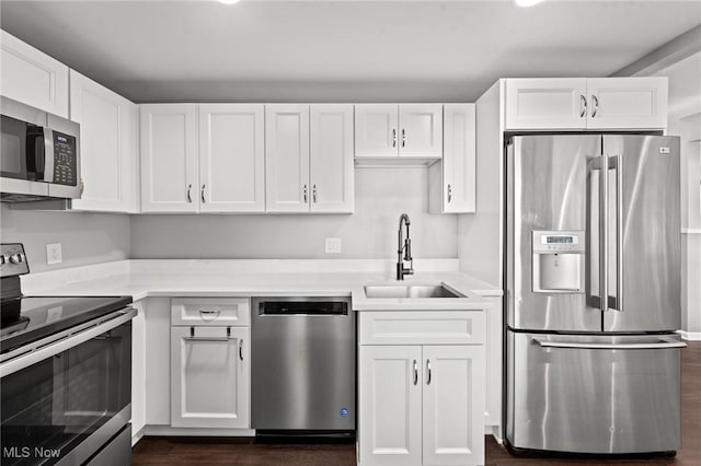 kitchen with stainless steel appliances, sink, dark wood-type flooring, and white cabinets