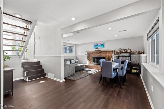 dining space featuring dark hardwood / wood-style flooring and a brick fireplace