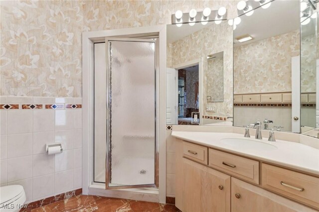 bathroom featuring vanity, toilet, tile walls, and a shower with shower door