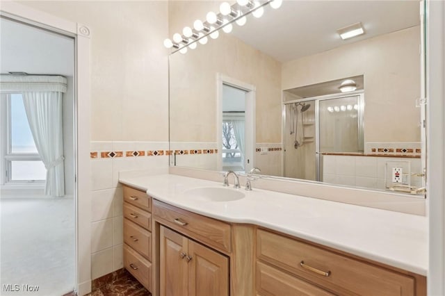 bathroom with vanity, a shower with shower door, and tile walls