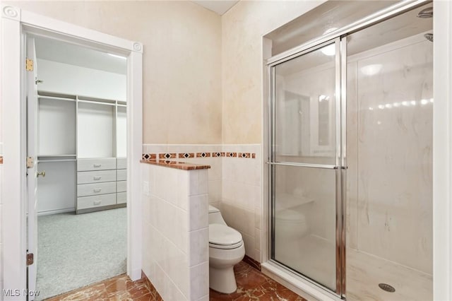 bathroom with tile walls, a shower with shower door, and toilet