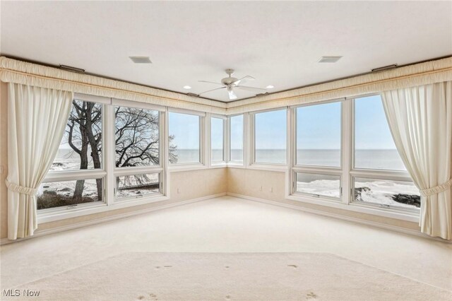 unfurnished sunroom with a water view and ceiling fan