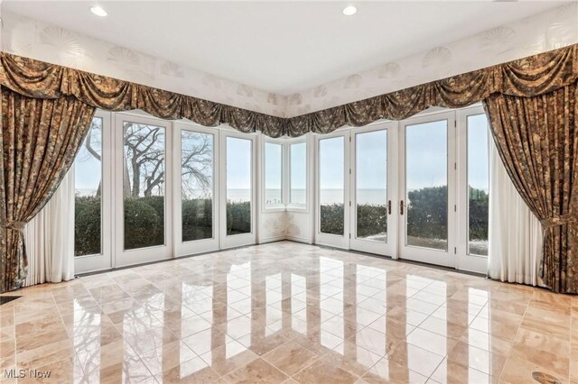 unfurnished sunroom with a wealth of natural light and a water view