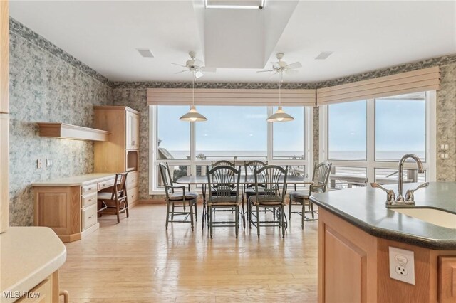 dining space featuring ceiling fan, built in desk, sink, and light wood-type flooring