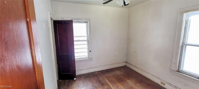 empty room featuring a healthy amount of sunlight, dark wood-type flooring, and ceiling fan