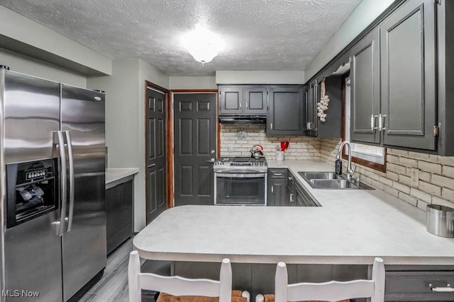 kitchen featuring tasteful backsplash, sink, a breakfast bar area, stainless steel appliances, and light hardwood / wood-style flooring