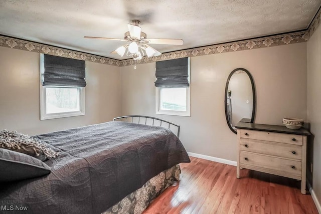 bedroom featuring ceiling fan, hardwood / wood-style floors, and a textured ceiling