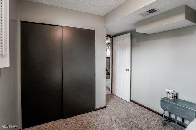 unfurnished bedroom with light colored carpet, a closet, and a textured ceiling