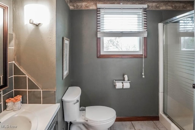 bathroom featuring vanity, toilet, tile patterned floors, and a shower with shower door