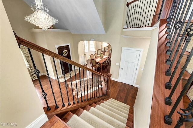 stairs with a high ceiling, wood-type flooring, and a chandelier