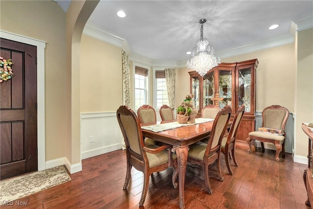 dining area featuring ornamental molding, dark wood-type flooring, and an inviting chandelier