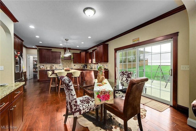 dining space with dark wood-type flooring, ornamental molding, and sink