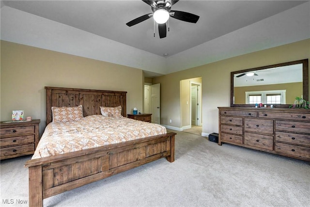 carpeted bedroom featuring a raised ceiling and ceiling fan