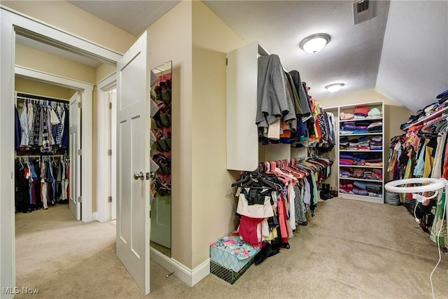 walk in closet featuring light carpet and vaulted ceiling