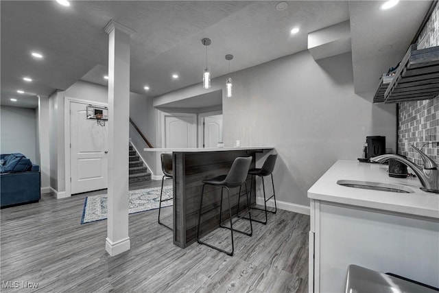 interior space featuring a breakfast bar, sink, white cabinetry, light hardwood / wood-style floors, and decorative backsplash