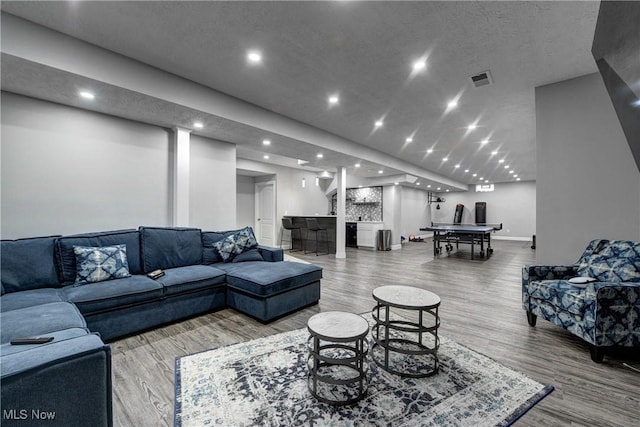 living room featuring hardwood / wood-style flooring, bar, and a textured ceiling