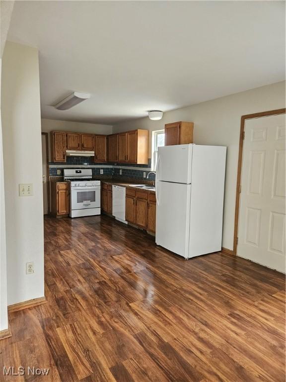 kitchen featuring tasteful backsplash, dark hardwood / wood-style floors, sink, and white appliances