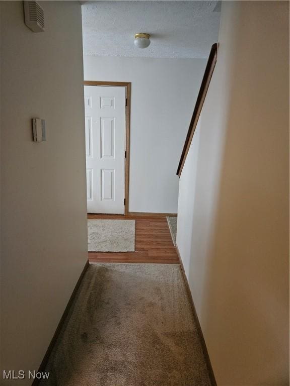 hallway with a textured ceiling and carpet flooring