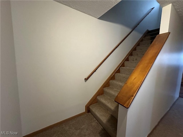 stairway featuring carpet floors and a textured ceiling