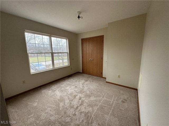 unfurnished bedroom with light colored carpet and a closet