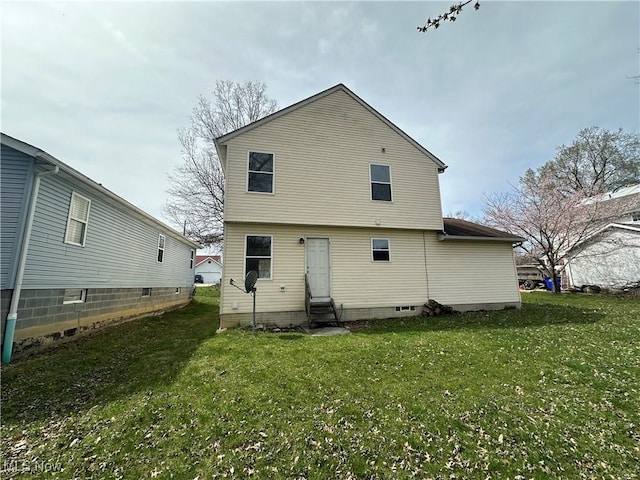 back of property with entry steps and a yard