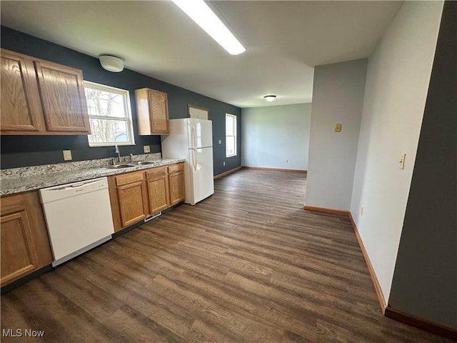 kitchen featuring baseboards, a sink, white appliances, dark wood finished floors, and brown cabinetry