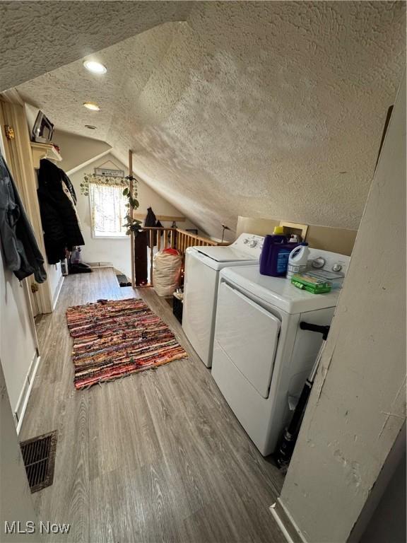 laundry area with separate washer and dryer, a textured ceiling, and light wood-type flooring