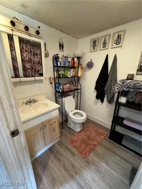 bathroom featuring vanity, hardwood / wood-style floors, a textured ceiling, and toilet