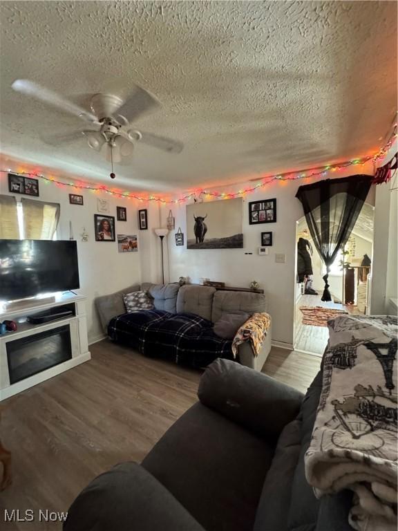 living room featuring hardwood / wood-style floors, a textured ceiling, ceiling fan, and a fireplace