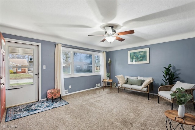 living area with light carpet, ceiling fan, and a textured ceiling