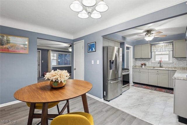 dining area with sink and ceiling fan with notable chandelier